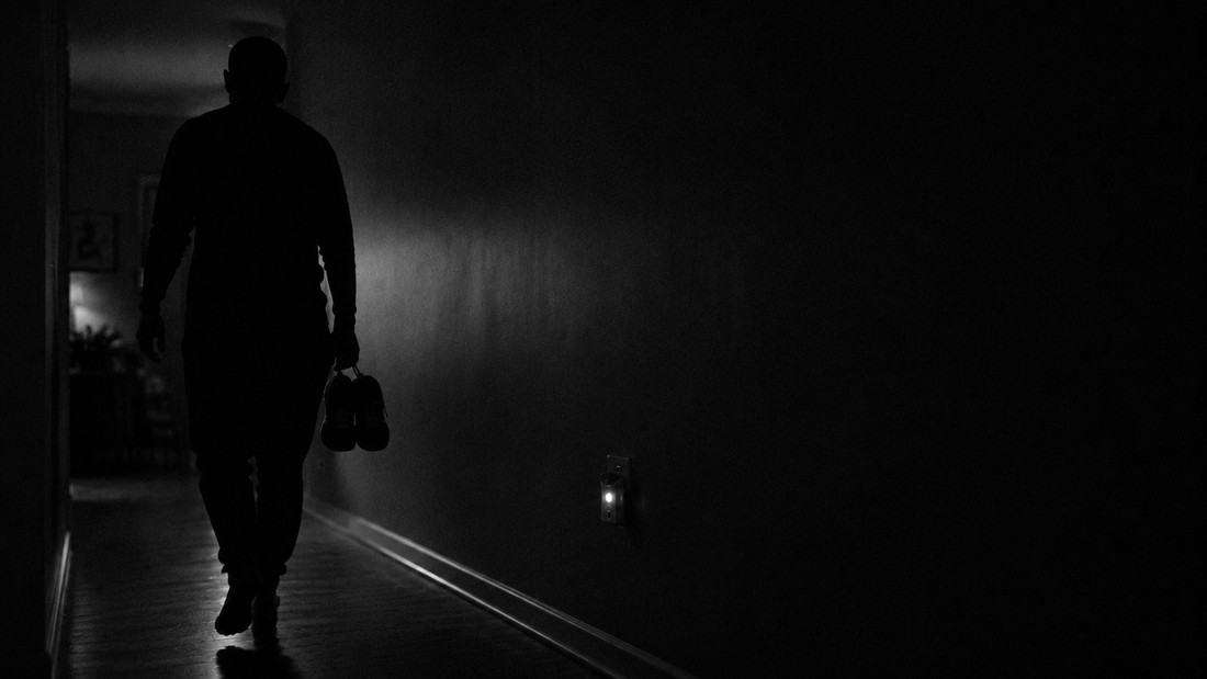 Man walking quietly down a dark hallway to train before his kids wake up